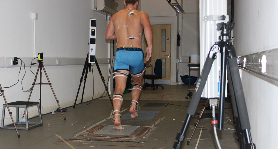 A rugby player running in a Sport Science room, attached to several biomechanics measuring tools