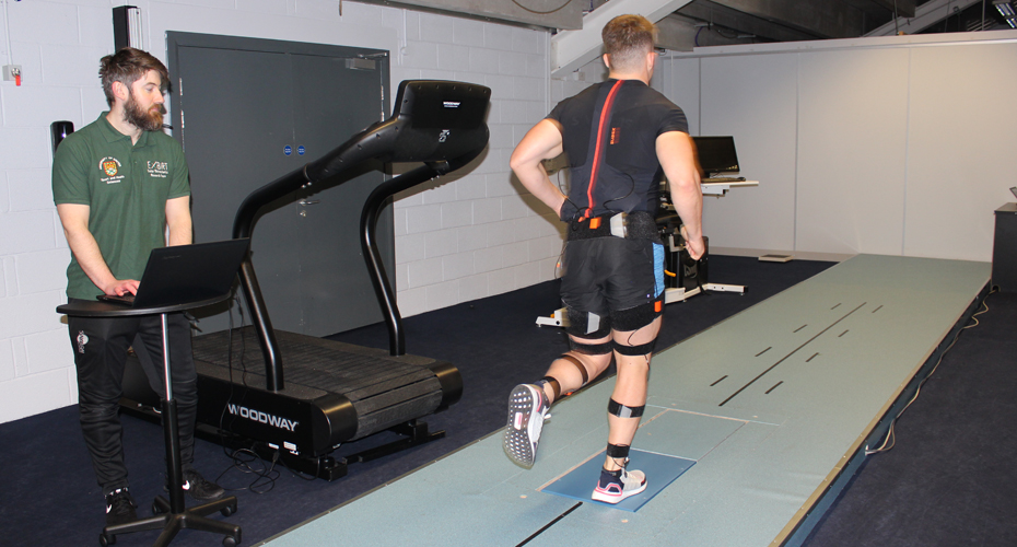 A rugby player running on a biomechanics machine, being monitored by a researcher at Exeter Chiefs' sports science lab