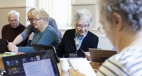 A group of older adults looking at computers