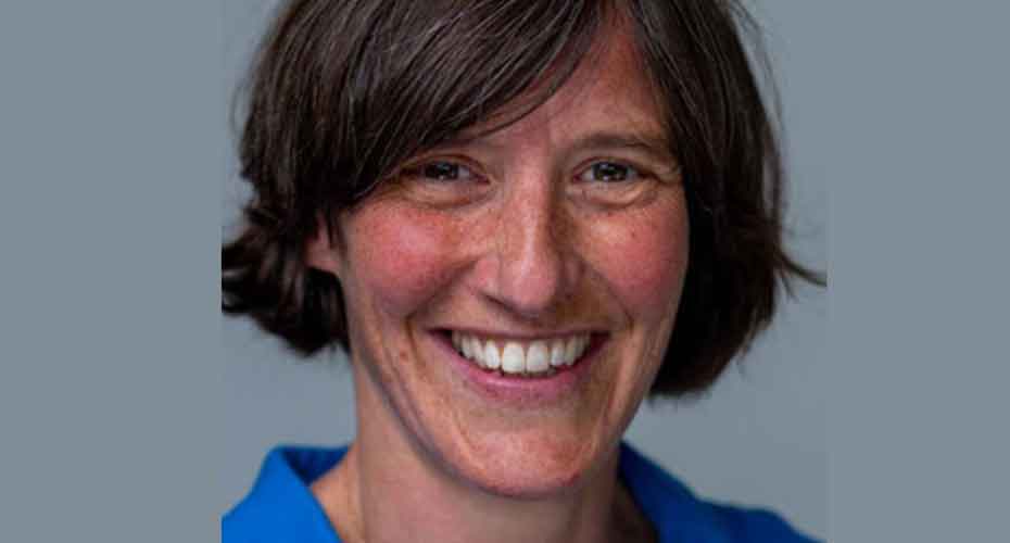 close up image of Emma smiling into camera with grey background