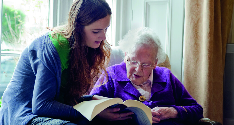 Student reading to elderly lady
