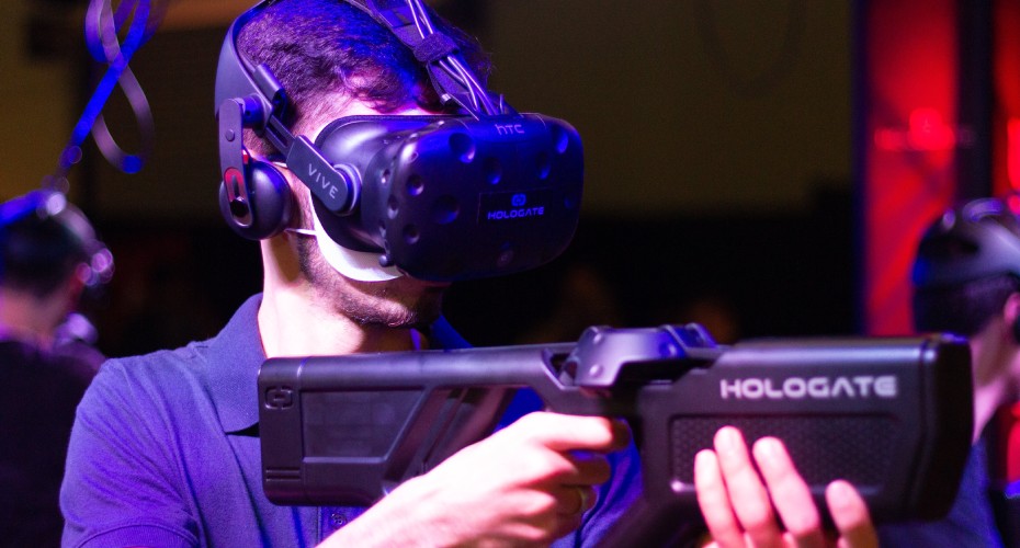 A man wearing a VR headset, holding a gun in a virtual reality simulation.