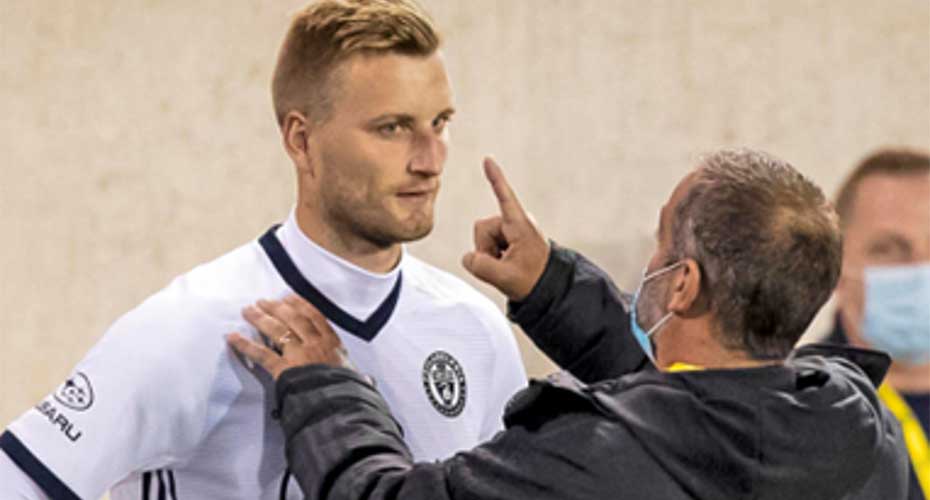 A coach holds up a finger to a footballer's eyes, checking for concussion