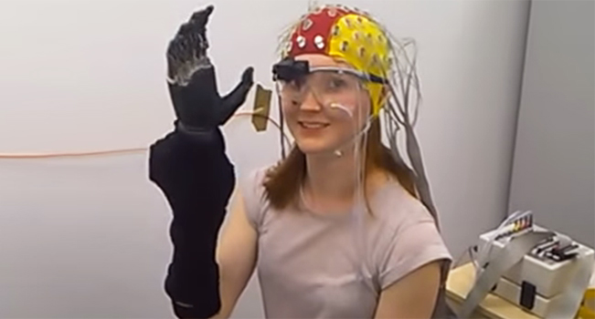 A woman with a prosthetic hand, wearing an EEG electrode cap